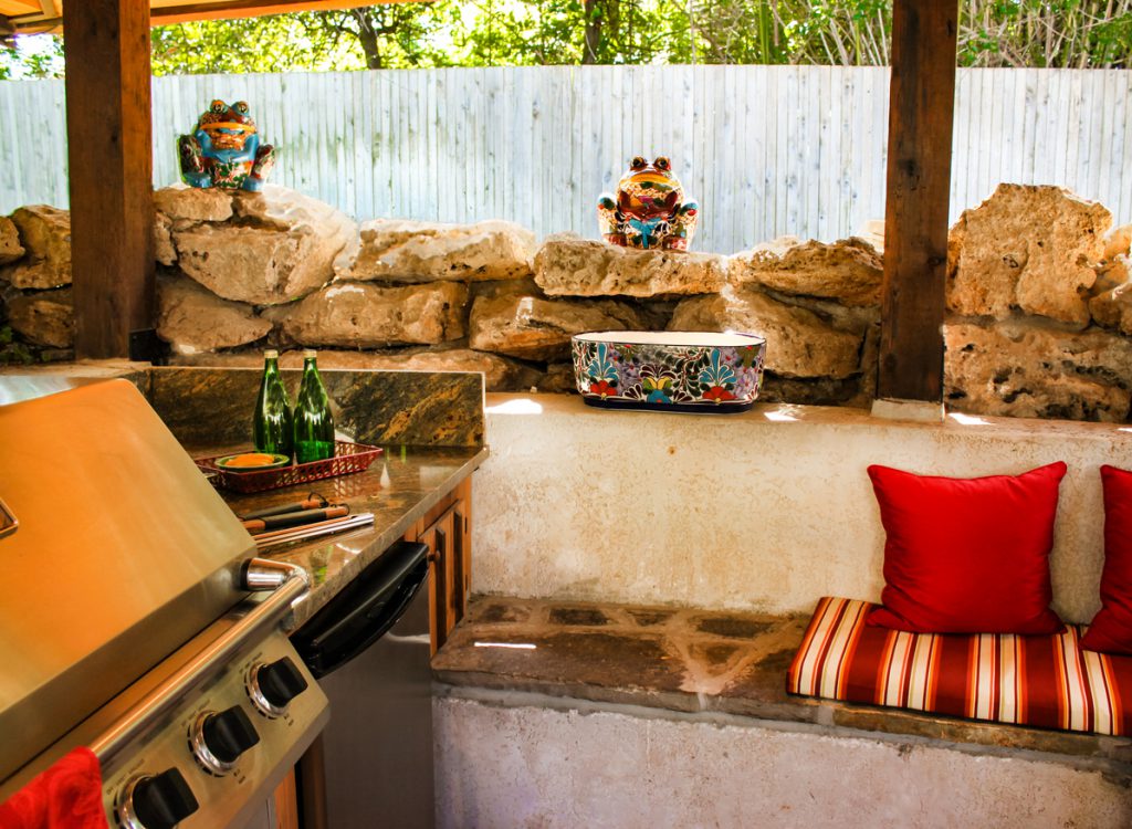 Outdoor barbeque area with stone benches and cushions and electric grill