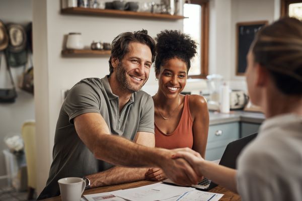 Couple Finances Home A couple shakes hands with a financial advisor in agreement about a home financing plan.