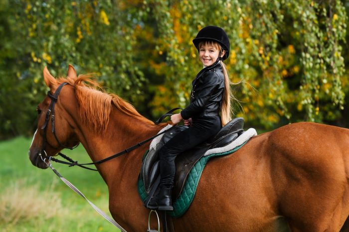 Young girl learning to ride a horse, one of the reasons families should move to Ocala, Florida. 