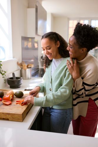 Mother and college aged daughter cooking together. 