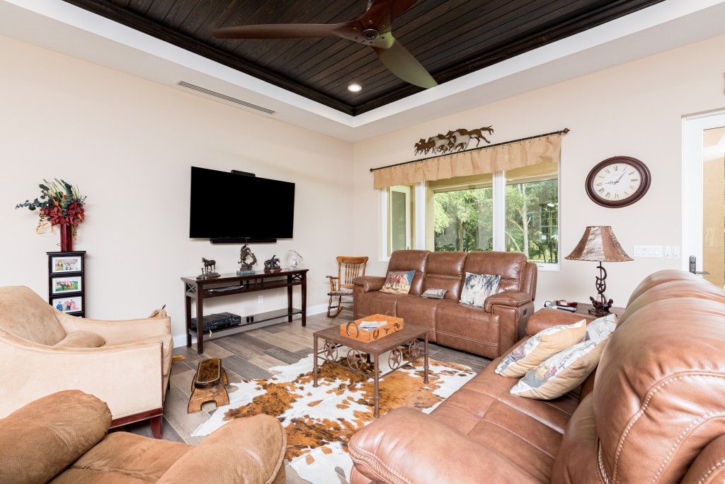 Living room featuring leather couches, a cowhide rug, equestrian decorations and family photos. 