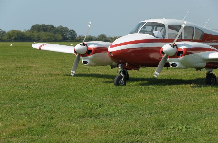 Small red and white personal plane parked in an airfield. 