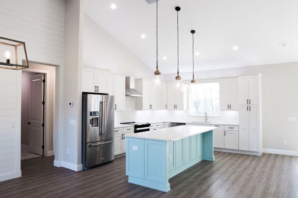 Kitchen with white countertops and a statement blue painted island. 